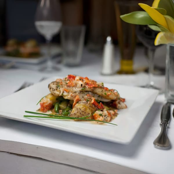 Italian seafood dish with lobster and green vegetables on a white plate at Cafe on the Green.