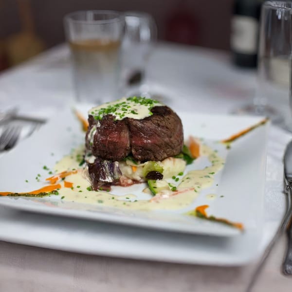 Cafe on the Green's Italian steak dish, topped with cream sauce and chives, served on a white plate.